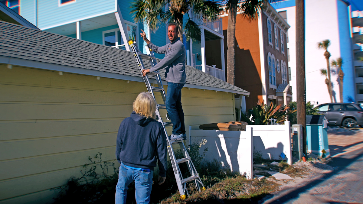 Roofing professional speaking with a homeowner beside a roof