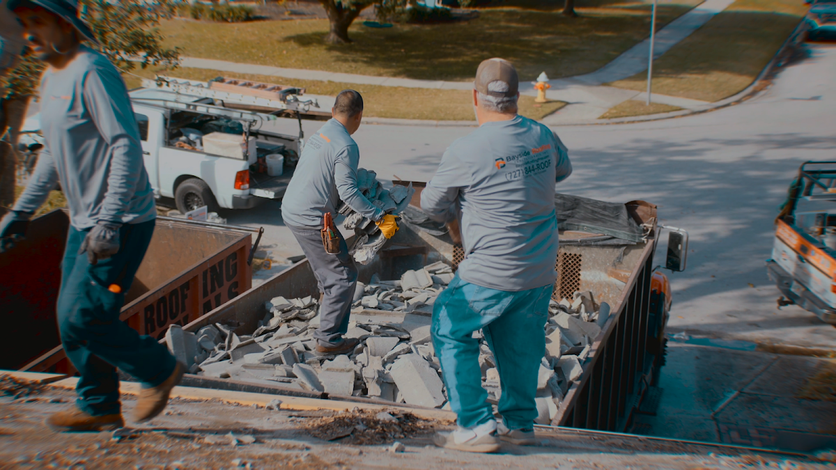 Roofing crew clearing removed material into a work truck
